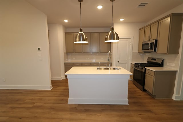 kitchen with sink, appliances with stainless steel finishes, dark hardwood / wood-style floors, a center island with sink, and decorative light fixtures