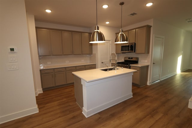 kitchen with dark hardwood / wood-style floors, pendant lighting, sink, a kitchen island with sink, and stainless steel appliances