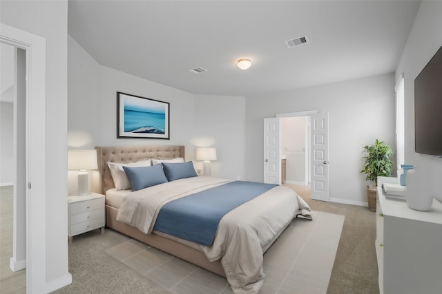 bedroom with ensuite bathroom and light colored carpet