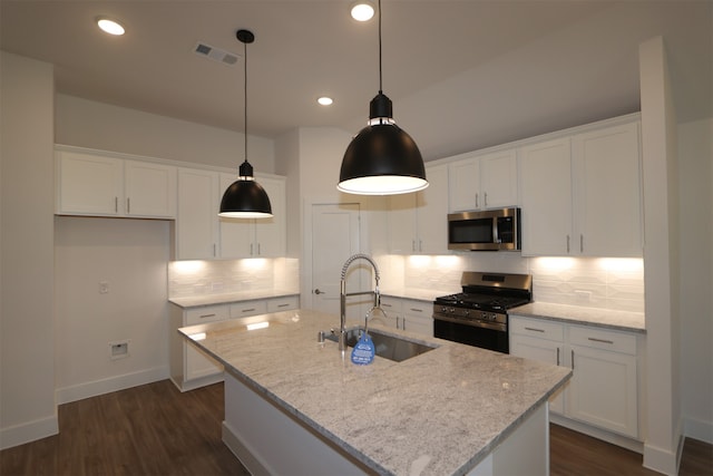 kitchen with stainless steel appliances, light stone countertops, and a center island with sink