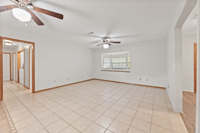 spare room featuring light tile patterned floors, a textured ceiling, ceiling fan, and washer / dryer