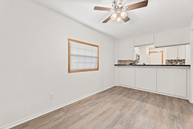 kitchen with white cabinetry, backsplash, light hardwood / wood-style flooring, and ceiling fan