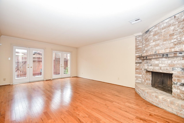 unfurnished living room featuring french doors, a brick fireplace, ornamental molding, and hardwood / wood-style flooring