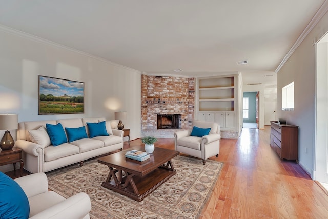 living room featuring light hardwood / wood-style flooring, built in features, crown molding, and a brick fireplace