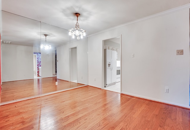 unfurnished room with light wood-type flooring, a notable chandelier, and ornamental molding