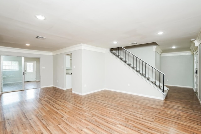 unfurnished living room featuring crown molding and light wood-type flooring