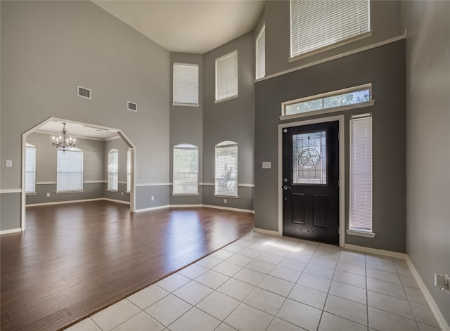 entryway featuring plenty of natural light, light hardwood / wood-style flooring, a towering ceiling, and a chandelier