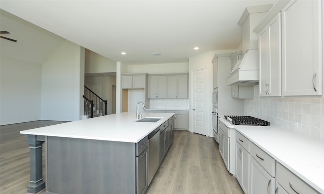 kitchen featuring tasteful backsplash, a kitchen island with sink, light hardwood / wood-style flooring, and appliances with stainless steel finishes