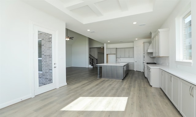 kitchen with tasteful backsplash, a breakfast bar, a kitchen island with sink, sink, and light hardwood / wood-style flooring