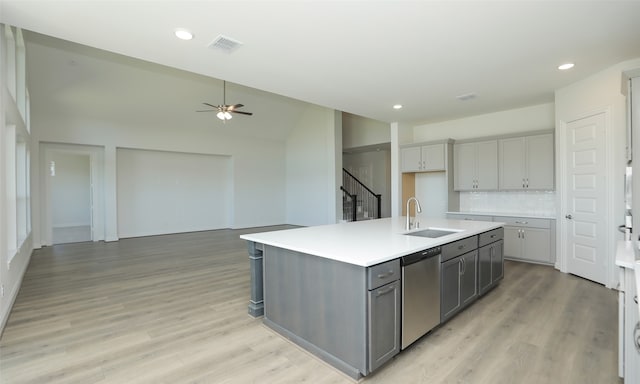 kitchen featuring a center island with sink, sink, light hardwood / wood-style flooring, stainless steel dishwasher, and gray cabinets