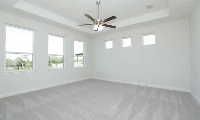 carpeted spare room with a raised ceiling and ceiling fan