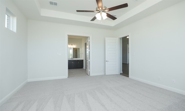 carpeted spare room featuring a tray ceiling and ceiling fan