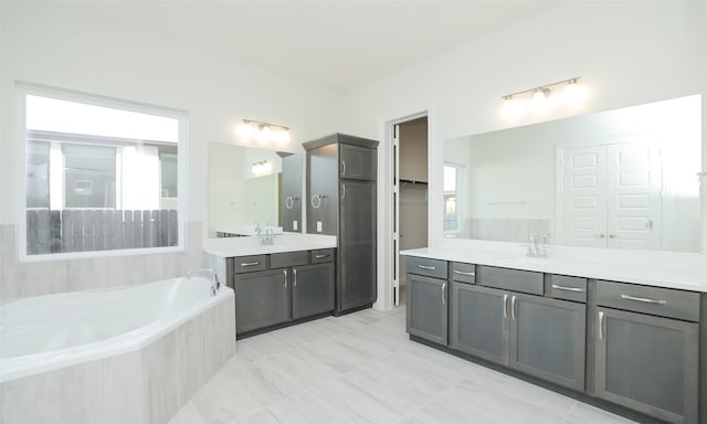 bathroom featuring tiled tub and vanity