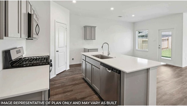 kitchen featuring sink, gray cabinets, an island with sink, dark hardwood / wood-style flooring, and stainless steel appliances