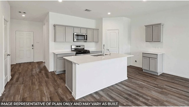 kitchen with a center island with sink, dark hardwood / wood-style flooring, gray cabinetry, and stainless steel appliances