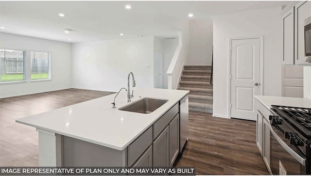 kitchen with a kitchen island with sink, dark wood-type flooring, sink, gray cabinets, and appliances with stainless steel finishes