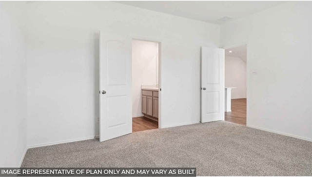 unfurnished bedroom featuring ensuite bathroom and light colored carpet