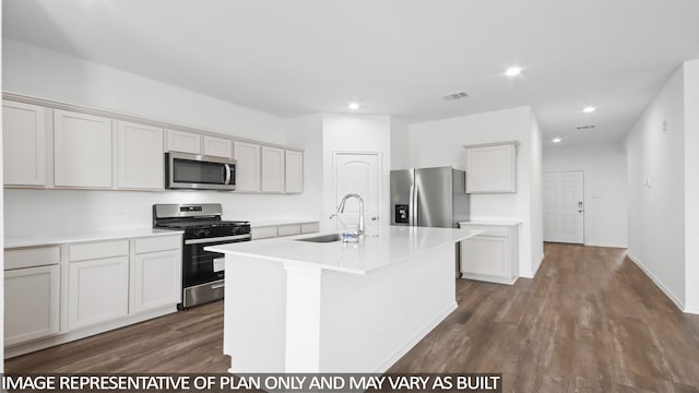 kitchen with appliances with stainless steel finishes, a center island with sink, dark hardwood / wood-style floors, and sink