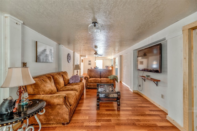 living room featuring ceiling fan, light hardwood / wood-style floors, and a textured ceiling