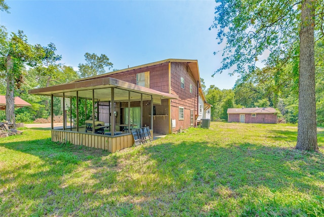 back of house with a lawn, central AC unit, and an outdoor structure