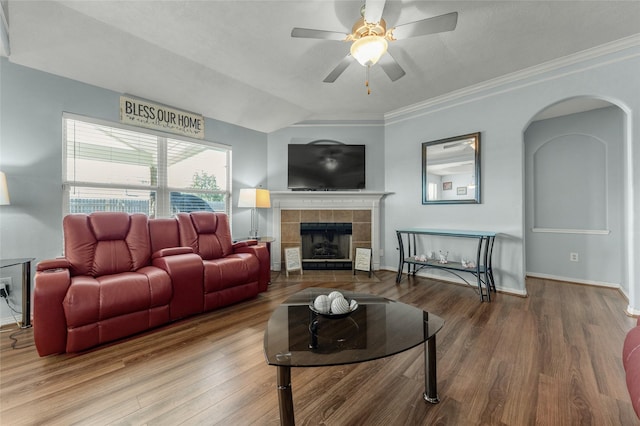 living room featuring crown molding, ceiling fan, hardwood / wood-style floors, a tiled fireplace, and vaulted ceiling