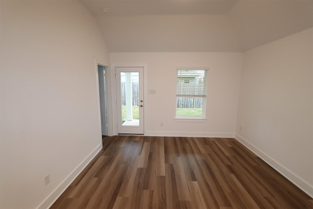 spare room with lofted ceiling and dark wood-type flooring