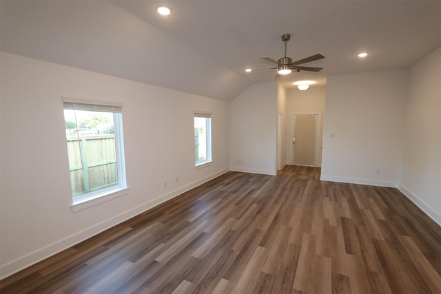 empty room featuring ceiling fan, dark hardwood / wood-style flooring, lofted ceiling, and a wealth of natural light