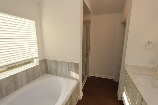 bathroom featuring hardwood / wood-style floors, vanity, and plus walk in shower