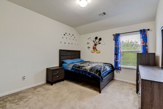 bedroom featuring vaulted ceiling, a textured ceiling, and light colored carpet