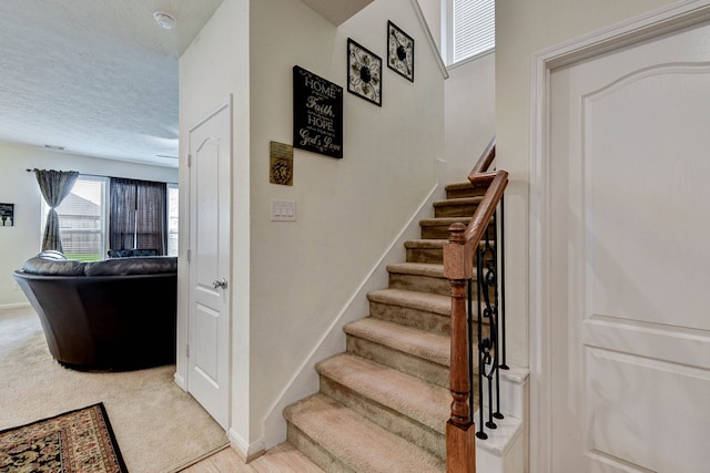 stairs featuring a textured ceiling and carpet flooring