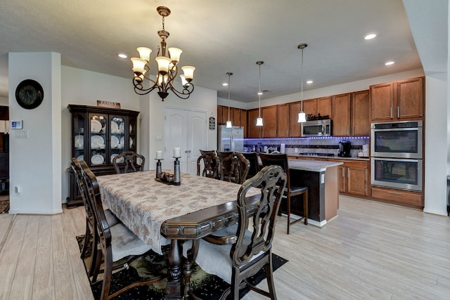 dining space with a notable chandelier and light hardwood / wood-style flooring