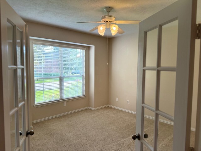 carpeted spare room featuring a textured ceiling, french doors, and ceiling fan