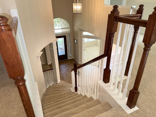 stairs with a towering ceiling and carpet floors