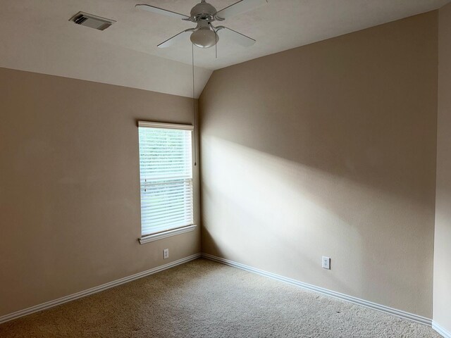 carpeted spare room featuring vaulted ceiling and ceiling fan