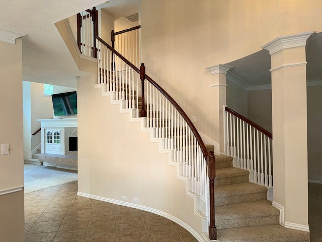 stairs featuring ornamental molding, ornate columns, tile patterned flooring, and a towering ceiling