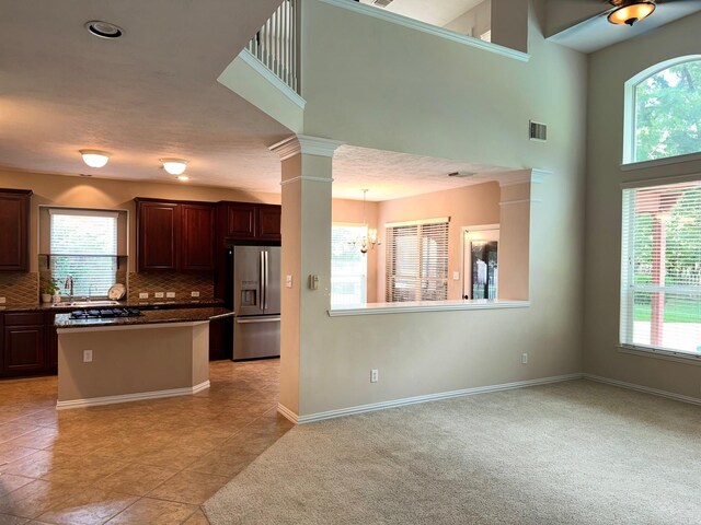 kitchen with decorative columns, an inviting chandelier, light colored carpet, decorative backsplash, and stainless steel fridge