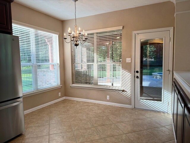 unfurnished dining area with an inviting chandelier and light tile patterned floors