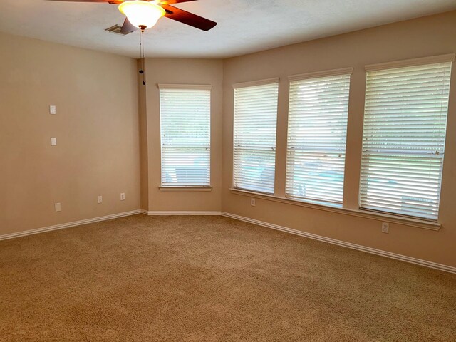 carpeted empty room with a healthy amount of sunlight and ceiling fan