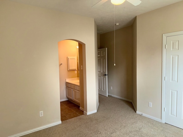 unfurnished bedroom featuring carpet, ceiling fan, and connected bathroom