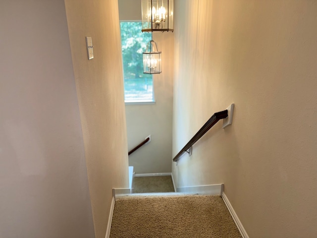 stairway featuring carpet and a chandelier