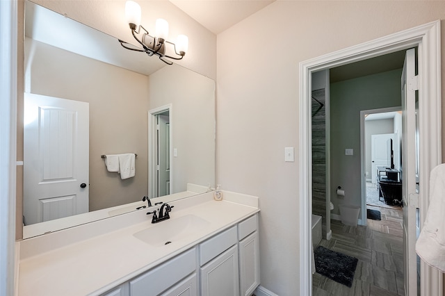 bathroom featuring a tub to relax in, vanity, toilet, and a chandelier