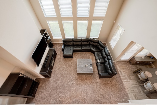 living room with a towering ceiling, plenty of natural light, and carpet flooring