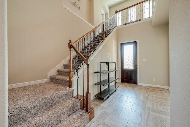 entrance foyer featuring light carpet and a towering ceiling