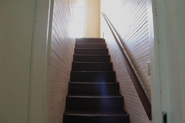 stairway featuring wooden walls