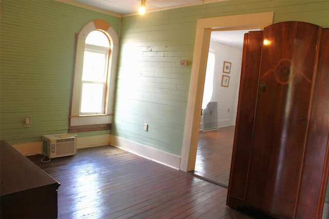 spare room featuring wood-type flooring and a wall mounted air conditioner