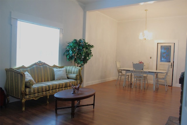 living room with dark hardwood / wood-style floors, crown molding, and an inviting chandelier