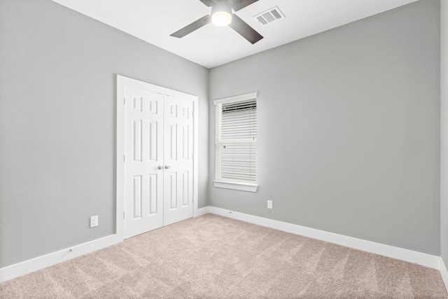 unfurnished bedroom with light colored carpet, ceiling fan, and a closet