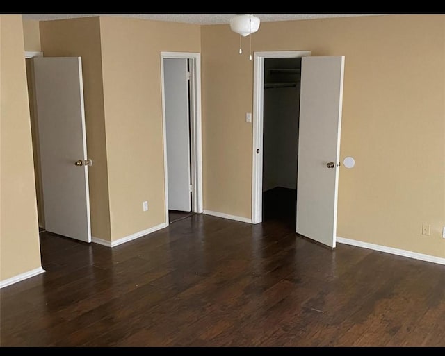 unfurnished bedroom featuring dark hardwood / wood-style flooring, a spacious closet, and a closet