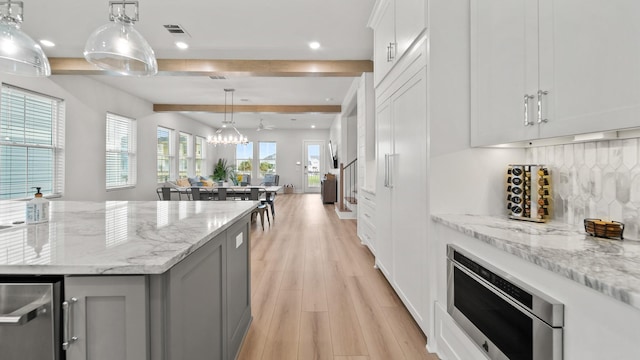 kitchen featuring visible vents, backsplash, gray cabinetry, stainless steel microwave, and light wood-style floors