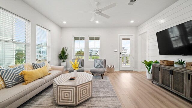 living room with a wealth of natural light, visible vents, light wood-style flooring, and recessed lighting